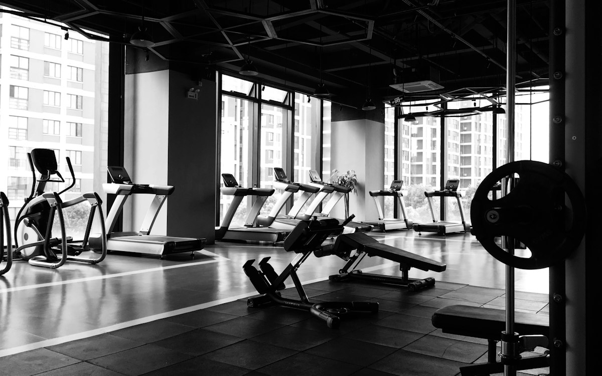 Weight benches and treadmills beside large gym windows